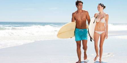 man and woman with surfboards on the beach