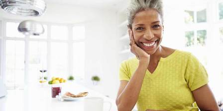 middle aged woman smiles at camera with chin on hand