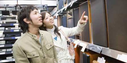 couple point at speakers in shop