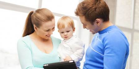 new parents and baby looking at tablet computer