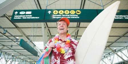 man with surfboard walking through airport