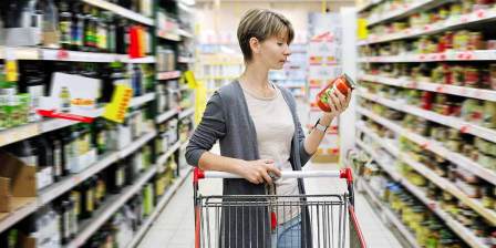 woman reading label on jar in supermarket
