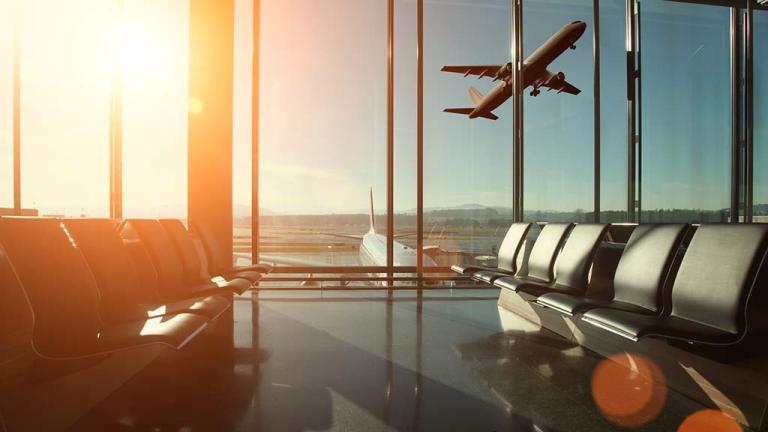 view out airport window of plane taking off