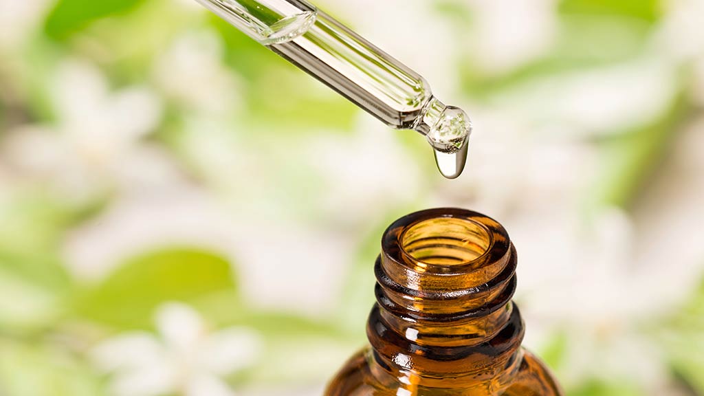 essential oil falling from glass dropper into bottle