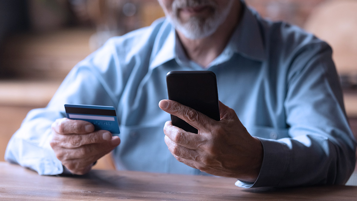 senior person on smartphone with credit card