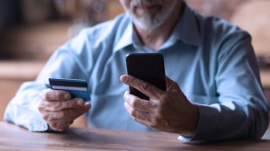 senior person on smartphone with credit card