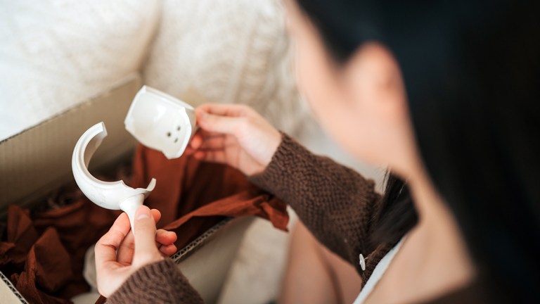 person_finding_broken_teapot_in_delivered_package