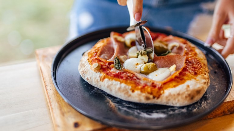rustic pizza being cut with a pizza slicer