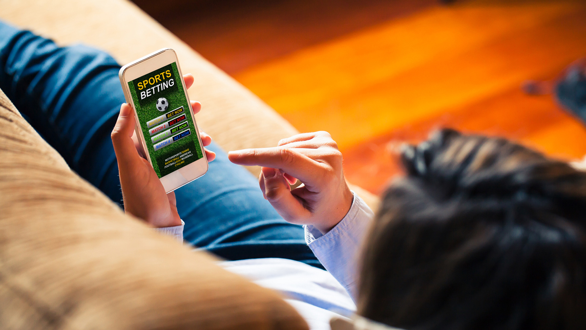 person holding phone with gambling sports app