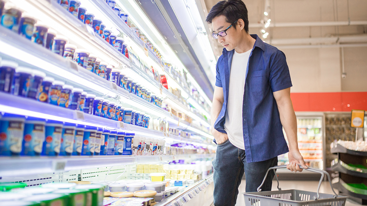 person shopping in the dairy aisle of supermarket