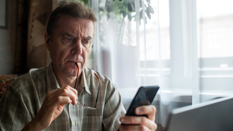 man_looking_at_phone_banking_scam_lead