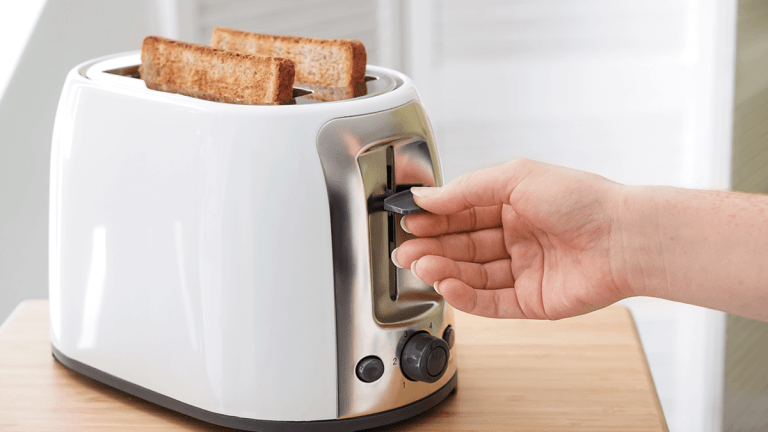 person toasting two slices of bread in a white toaster