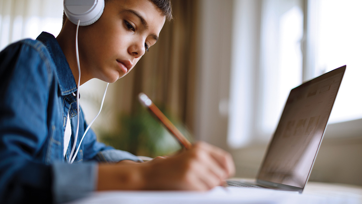 young boy doing homework on laptop