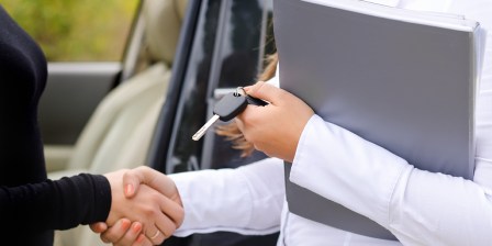 salesperson handing over keys to used car