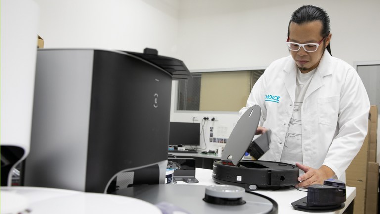 CHOICE tester Matthew Tung checking dust canister in a robot vacuum