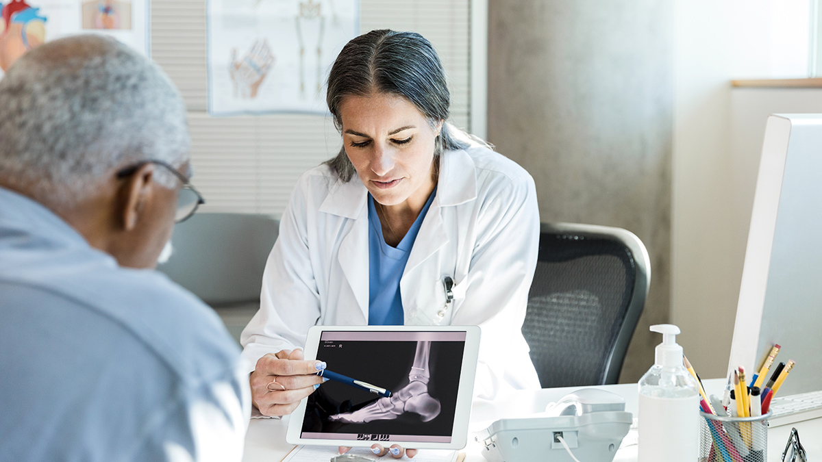 doctor_showing_foot_xray_on_tablet_to_senior_patient
