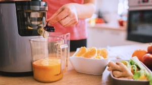 person_making_fruit_juice_using_electric_juicer