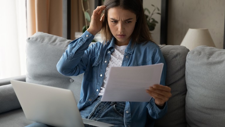 perplexed person looking at energy bill with laptop on lap