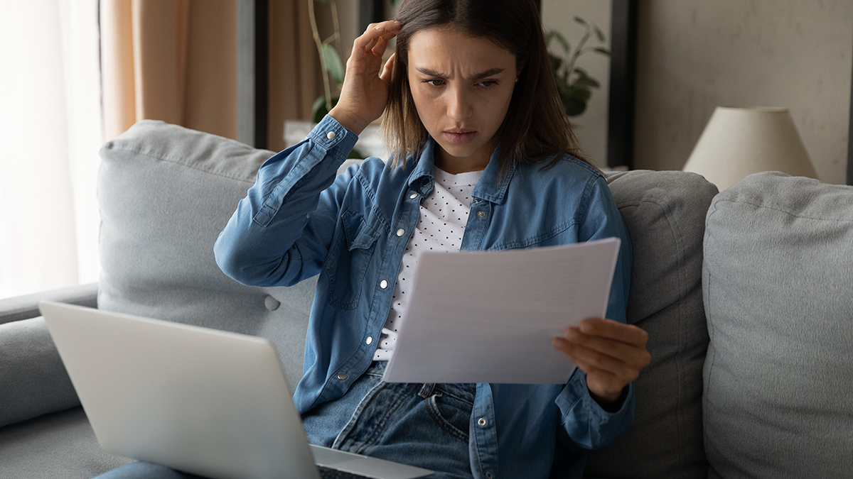 perplexed person looking at energy bill with laptop on lap