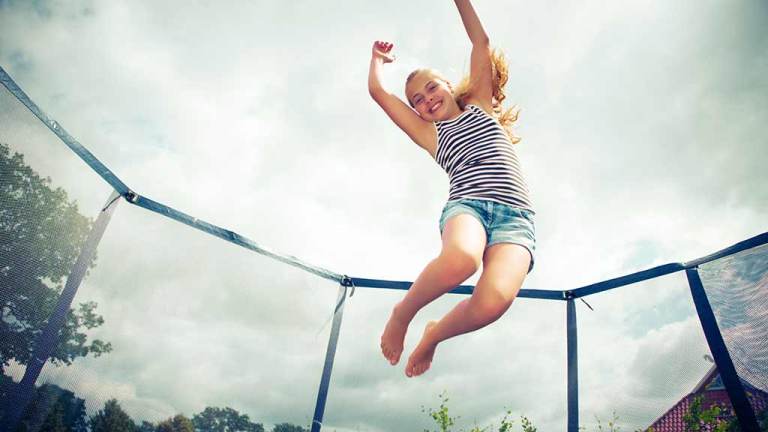 child_jumping_on_trampoline_in_backyard