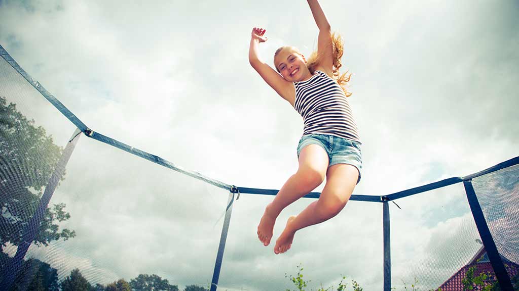 child_jumping_on_trampoline_in_backyard