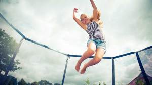child_jumping_on_trampoline_in_backyard