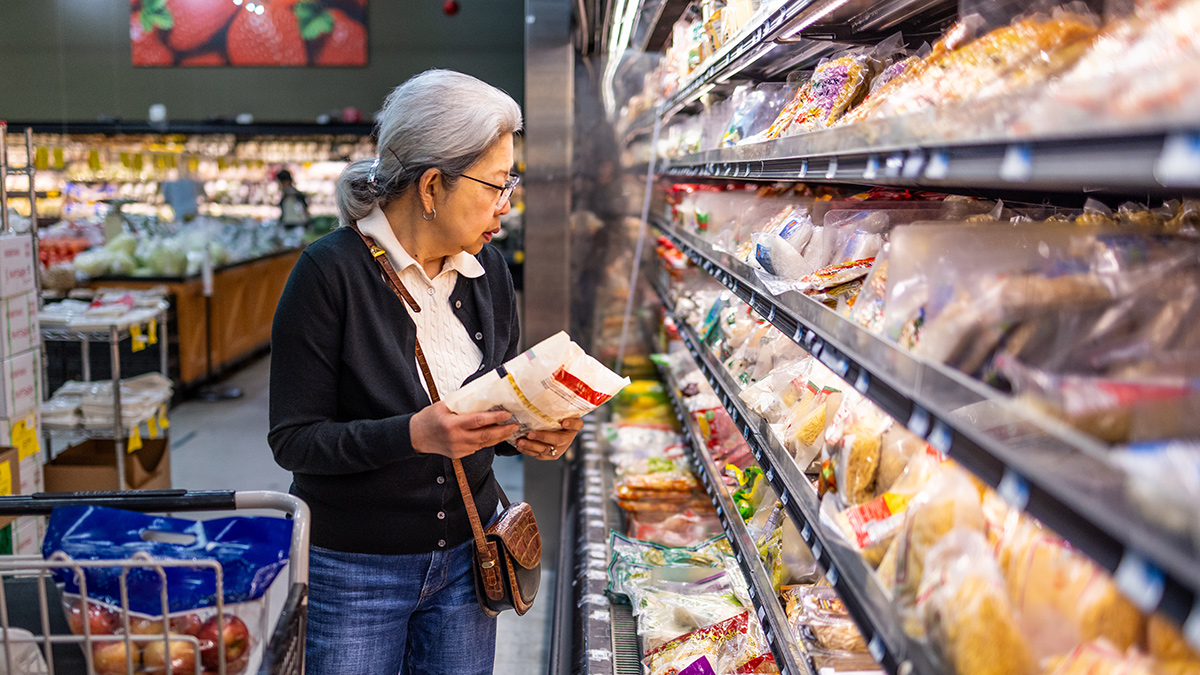 person checking unit pricing on price tags in supermarket